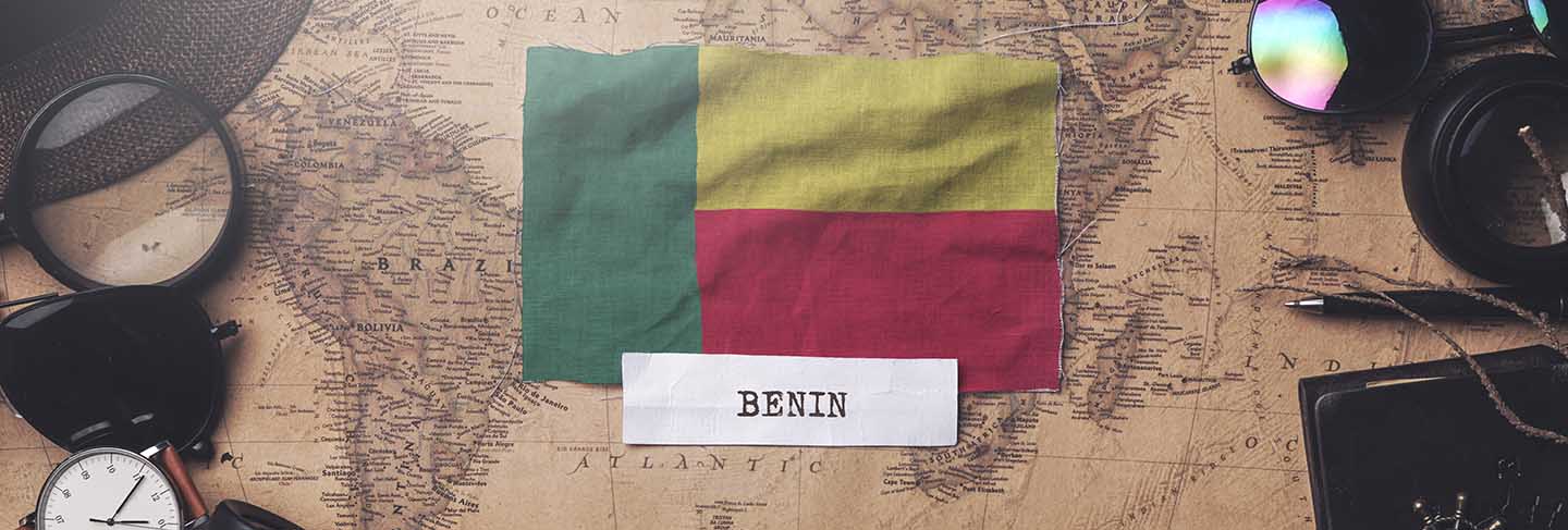 Benin flag between traveler's accessories on old vintage map