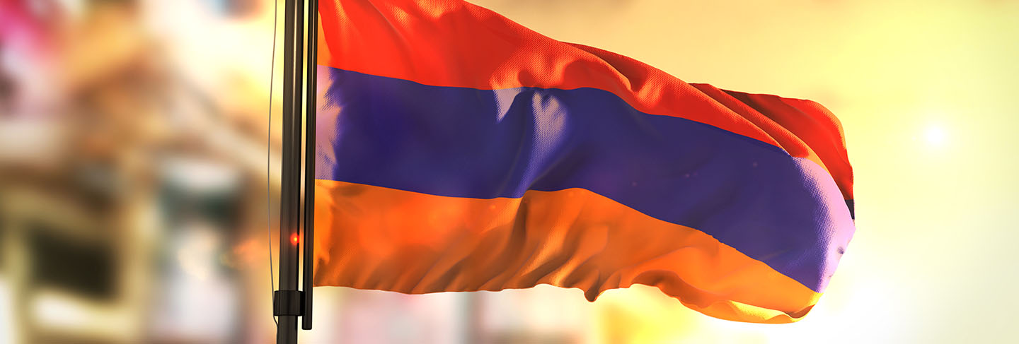 Armenia flag against city blurred background at sunrise backlight