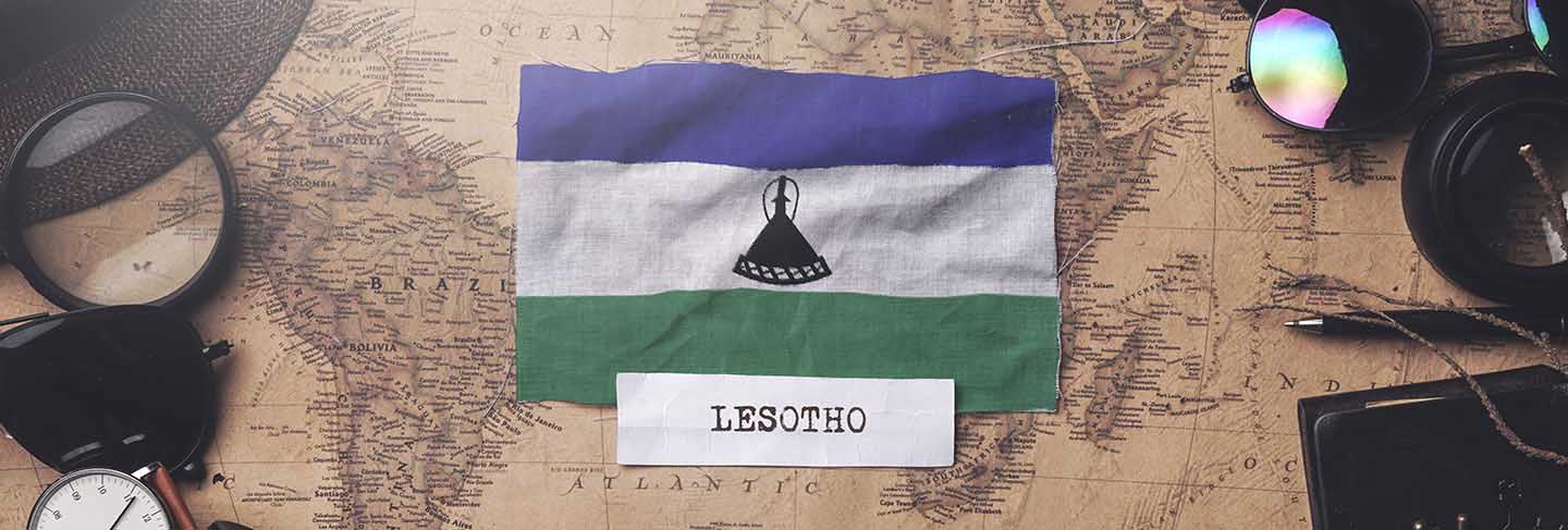 Lesotho flag between traveler's accessories on old vintage map