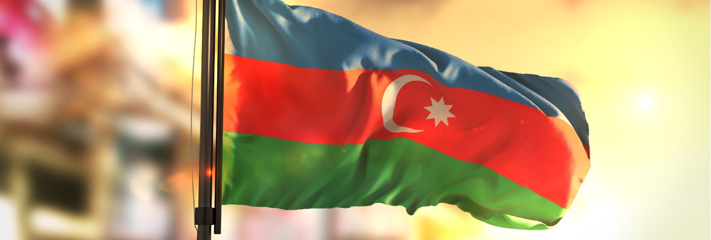 Azerbaijan flag against city blurred background at sunrise backlight