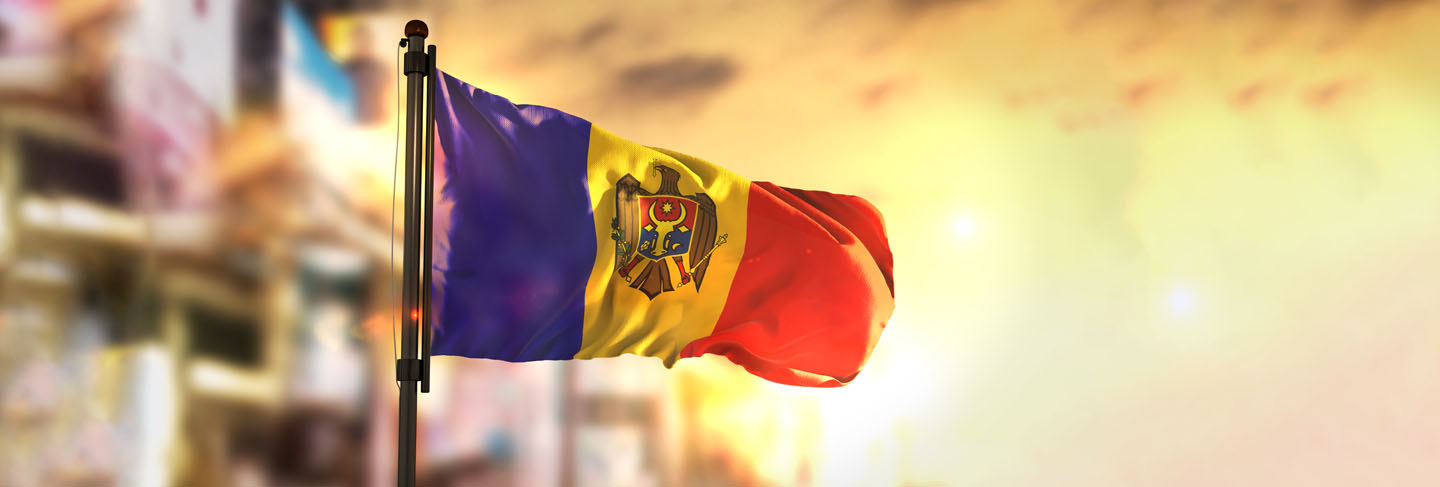 Moldova flag against city blurred background at sunrise backlight