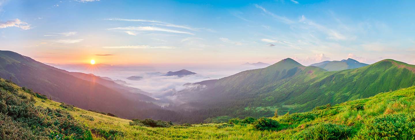 Beautiful sunrise in mountains with white fog below panorama