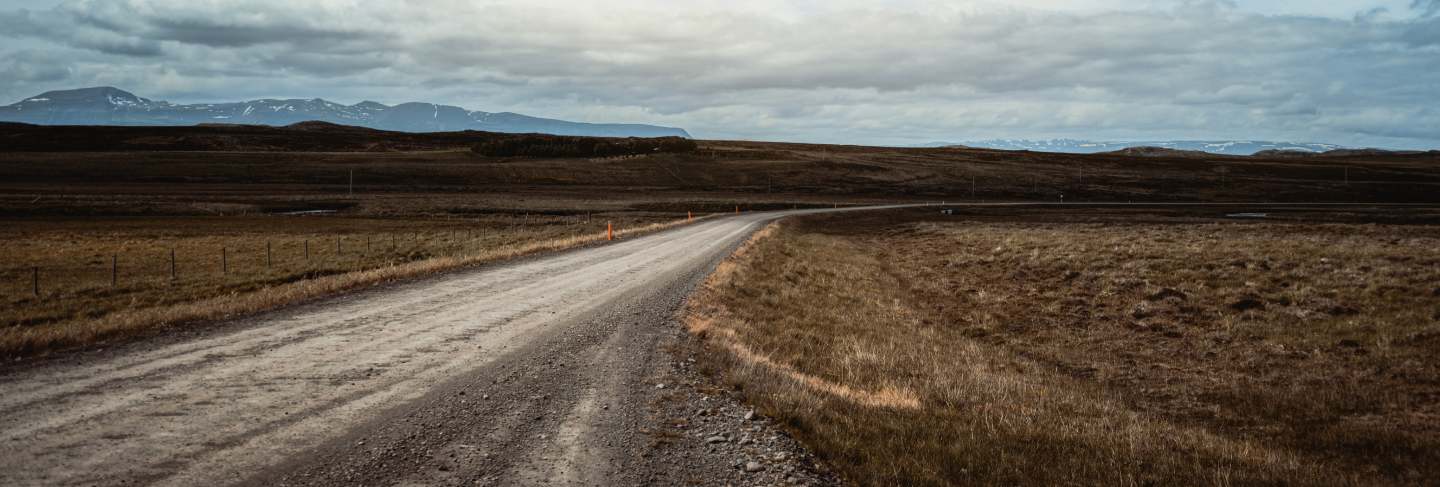 Empty dirt road through countryside landscape.