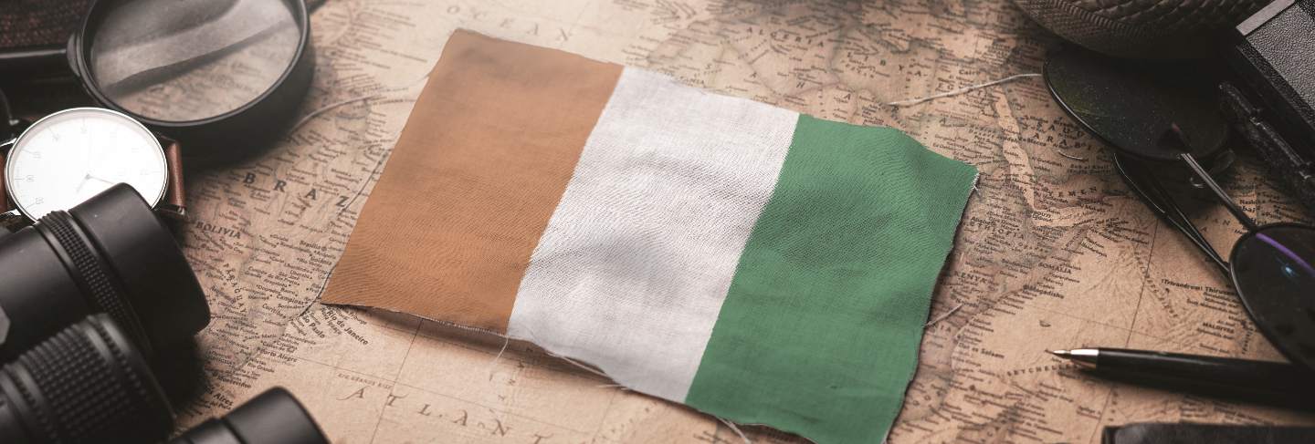 Ivory coast flag between traveler's accessories on old vintage map. tourist destination concept