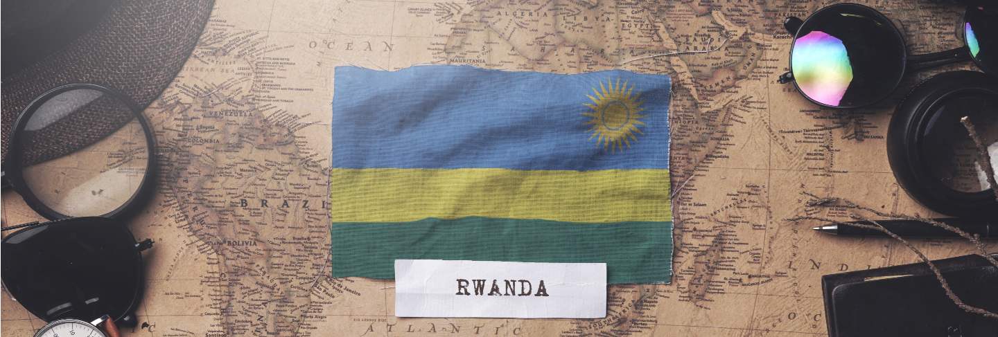 Rwanda flag between traveler's accessories on old vintage map