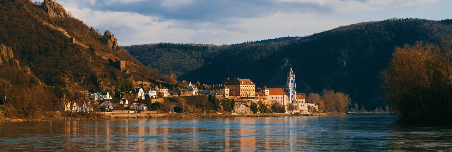 Photo of a small village bathed in sunlight near danube river in austria. places t see while traveling.
