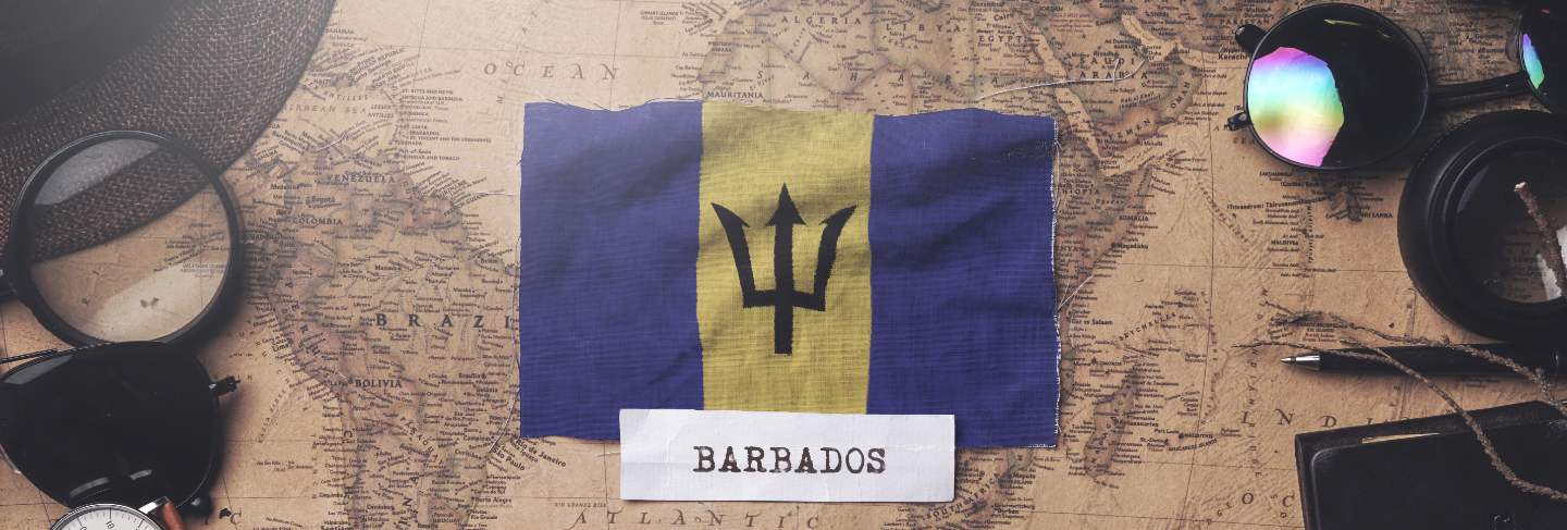 Barbados flag between traveler's accessories on old vintage map.
