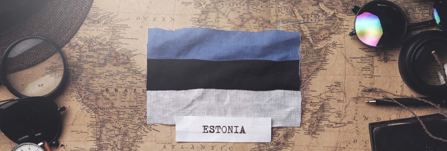 Estonia flag between traveler's accessories on old vintage map. overhead shot
