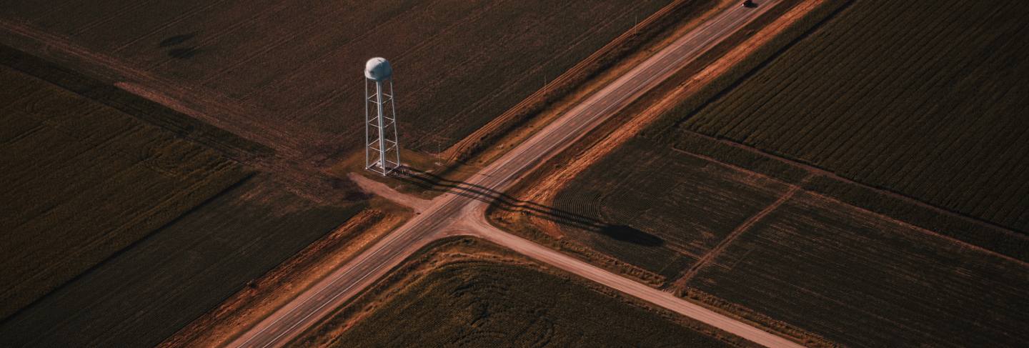 Beautiful aerial shot of narrow roads intersection in the countryside with a white tower

