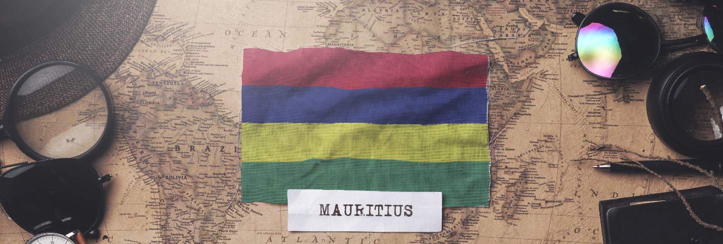 Mauritius flag between traveler's accessories on old vintage map. overhead shot