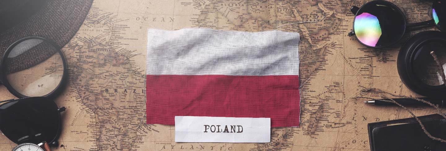 Poland flag between traveler's accessories on old vintage map. overhead shot
