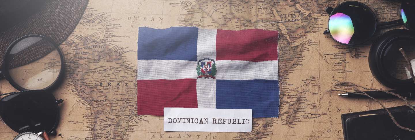 Dominican republic flag between traveler's accessories on old vintage map
