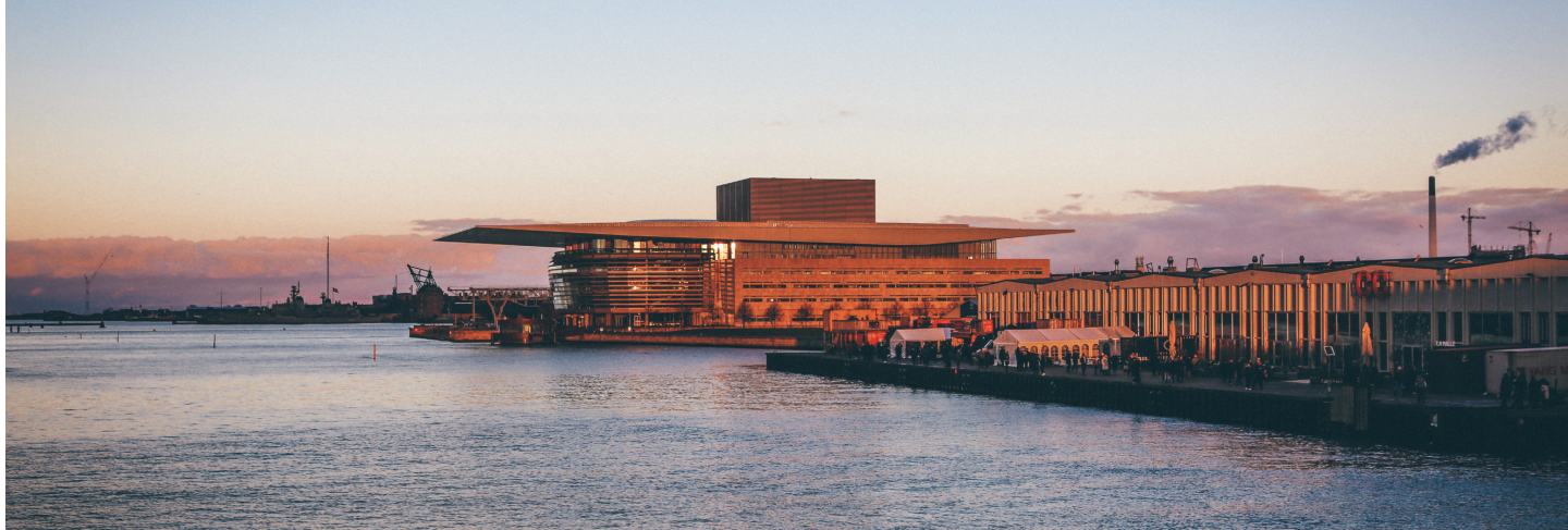 Wide shot of copenhagen opera house and street food markets by the body of water
