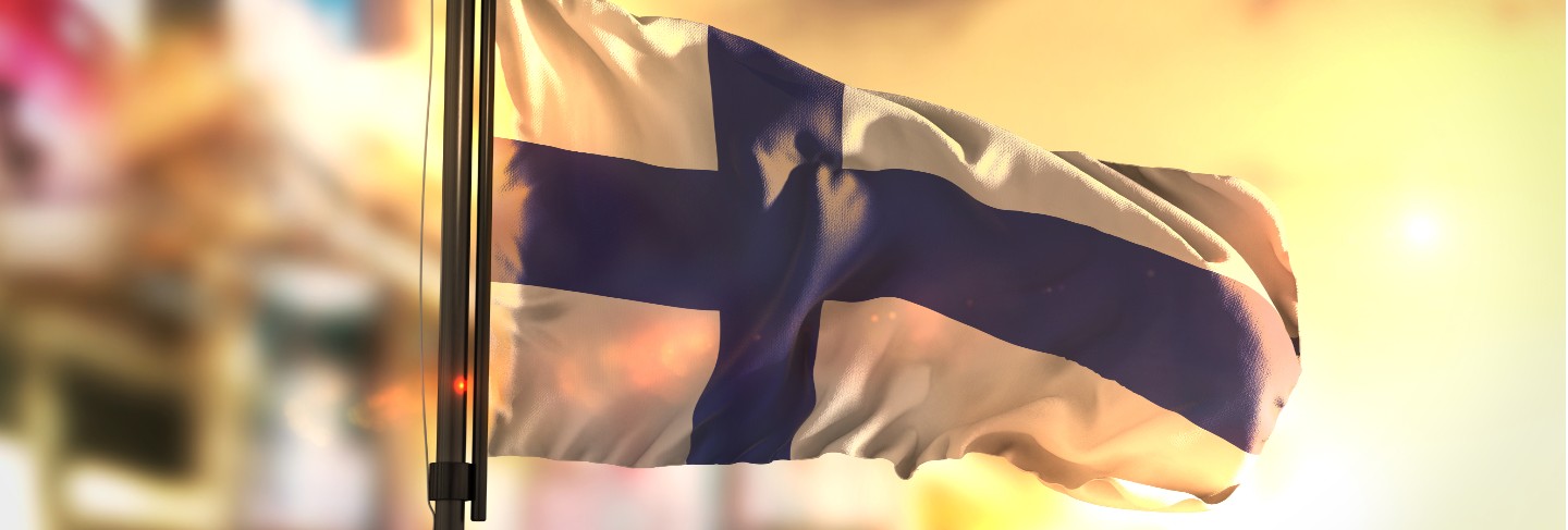 Finland flag against city blurred background at sunrise backlight 
