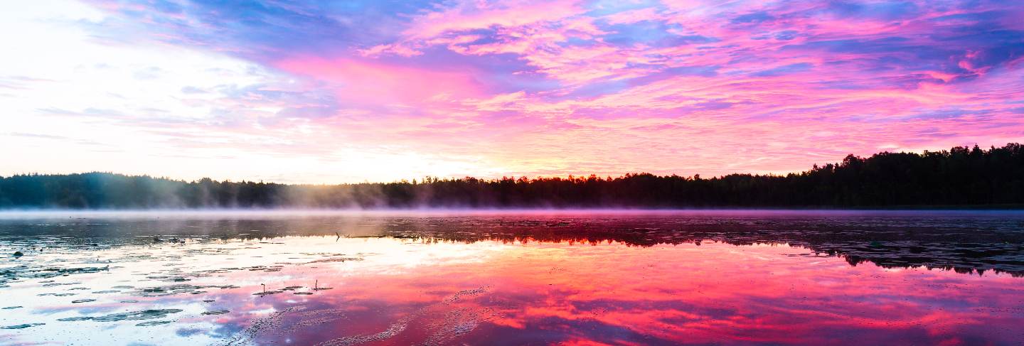 Bright colorful foggy sunset on the lake with clouds and reflections
