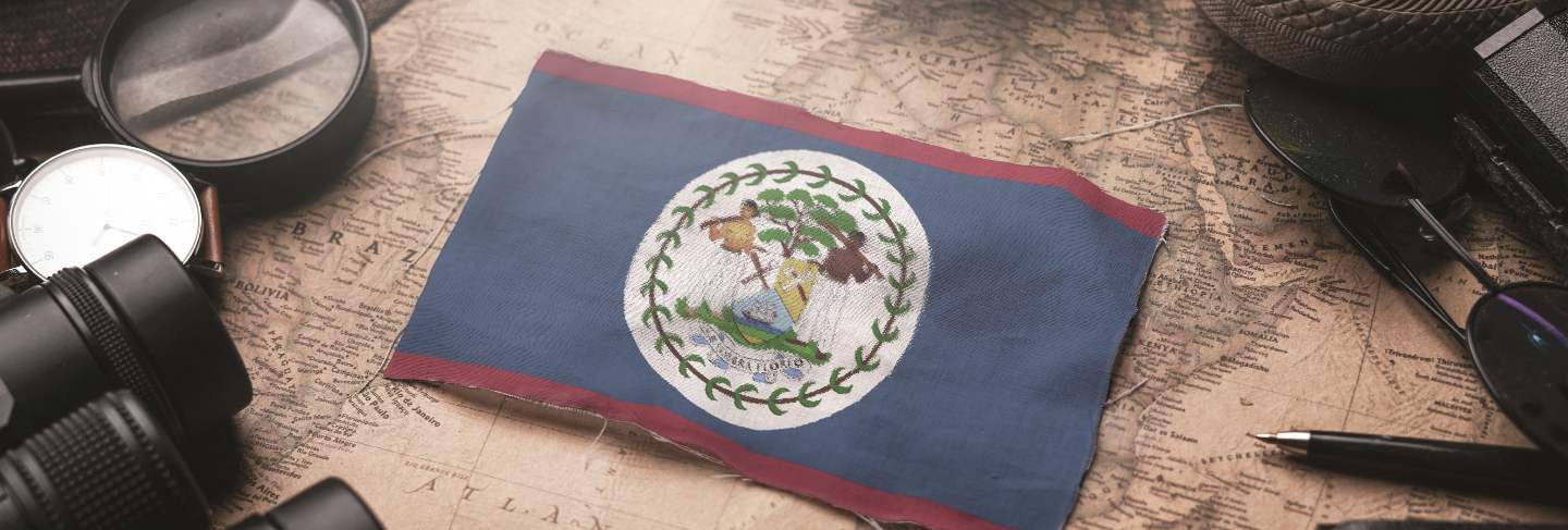 Belize flag between traveler's accessories on old vintage map. tourist destination concept.