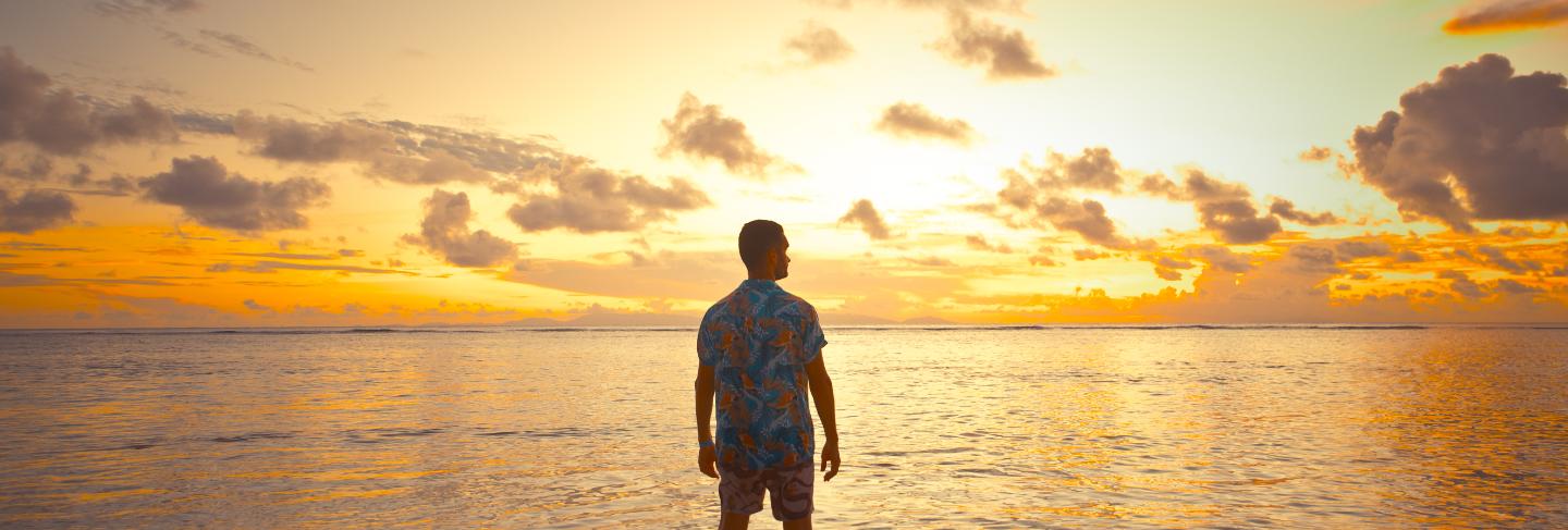 Tropical sunset in front of the ocean on a beautiful island. man on vacation enjoying the moment