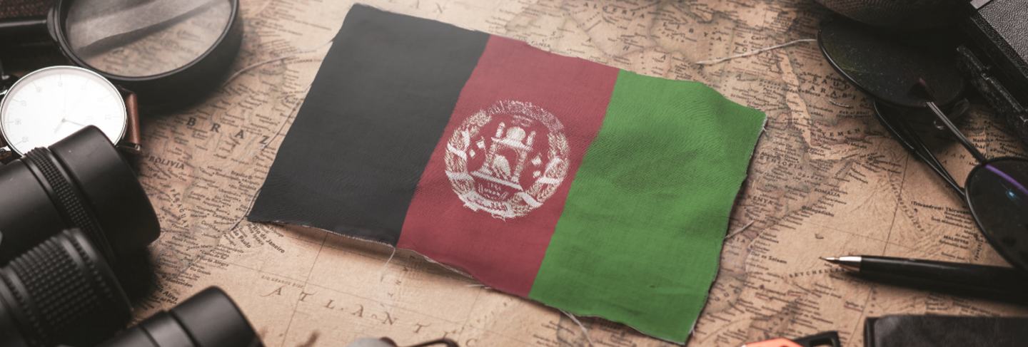 Afghanistan flag between traveler's accessories on old vintage map. tourist destination concept
