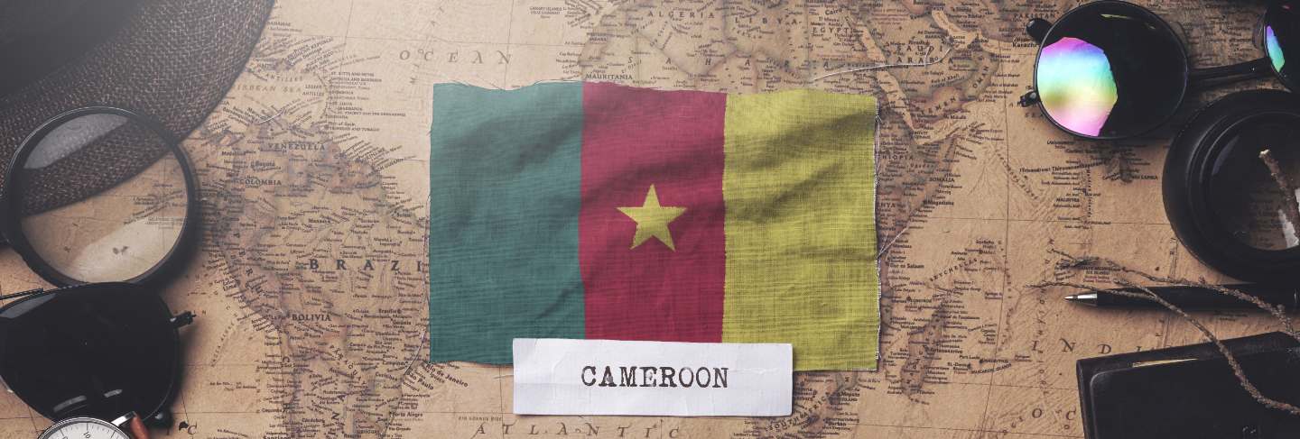 Cameroon flag between traveler's accessories on old vintage map. overhead shot