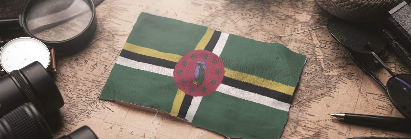 Dominica flag between traveler's accessories on old vintage map. tourist destination concept