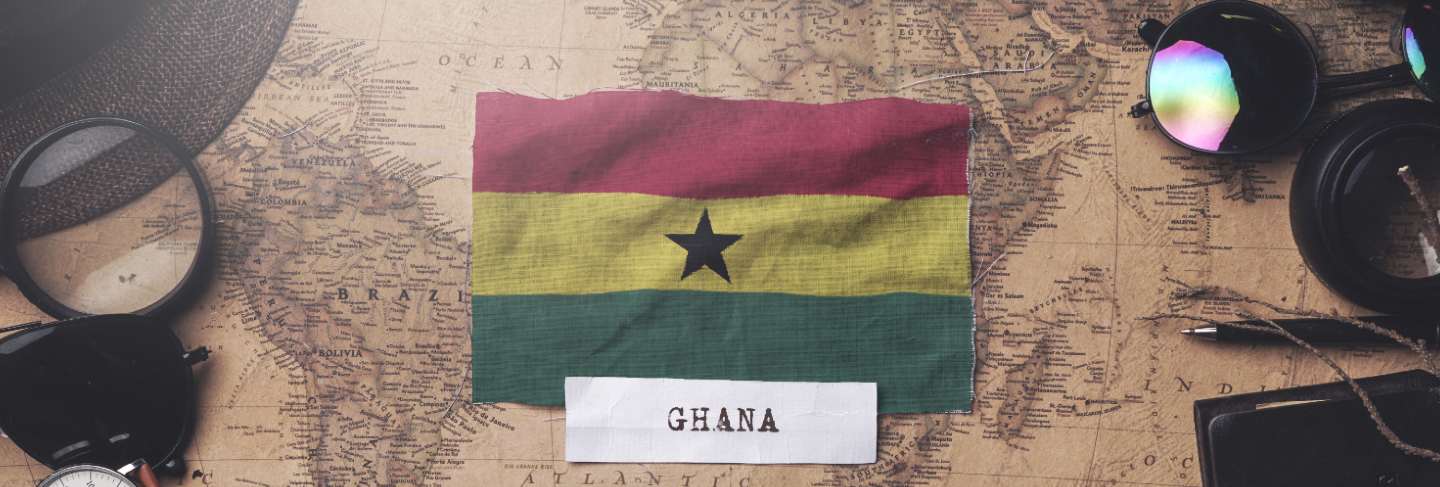 Ghana flag between traveler's accessories on old vintage map. overhead shot
