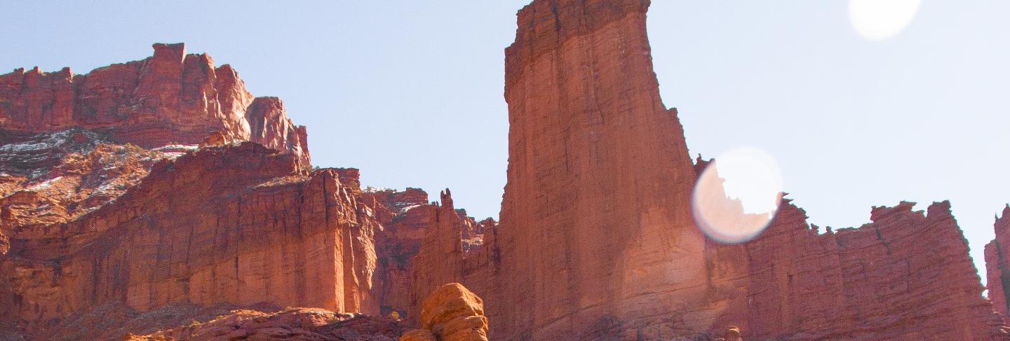 Vertical shot of people walking up the hill near a desert cliff at daytime 
