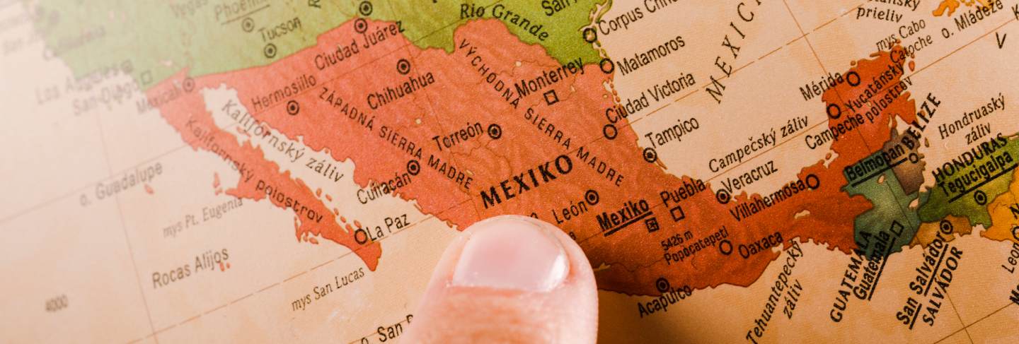 A person's finger showing mexico city on map
