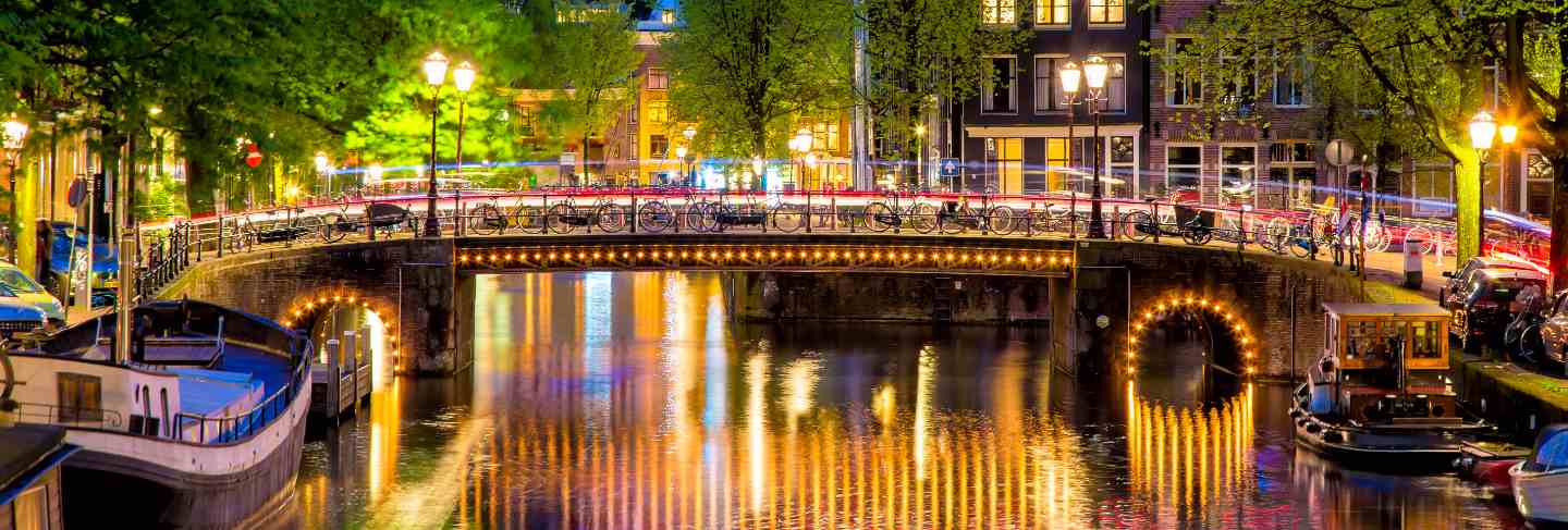 Amsterdam canal with typical dutch houses and bridge during twilight blue hour in holland, netherlands.
