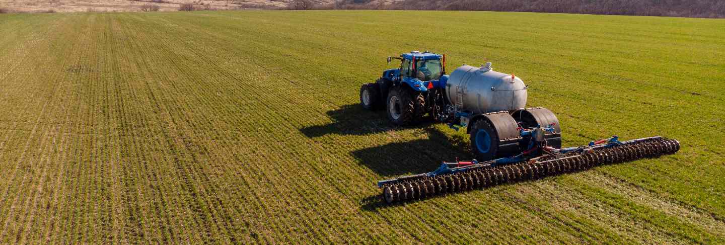 Tractor applying liquid mineral fertilizers to the soil on winter wheat