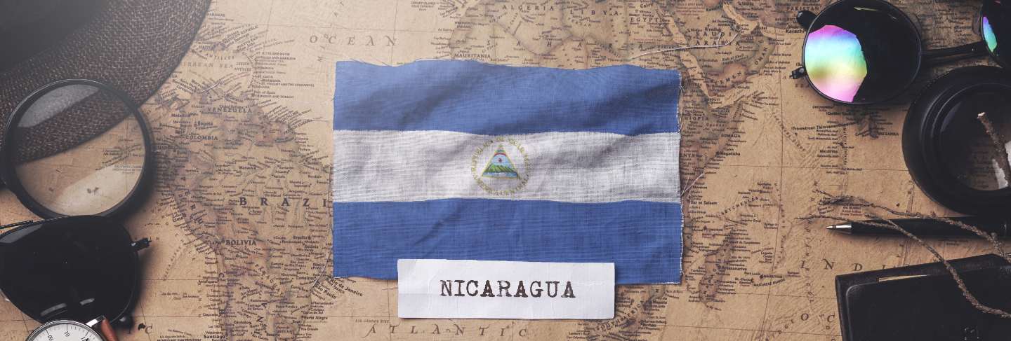 Nicaragua flag between traveler's accessories on old vintage map. overhead shot
