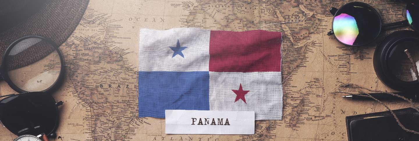 Panama flag between traveler's accessories on old vintage map. overhead shot
