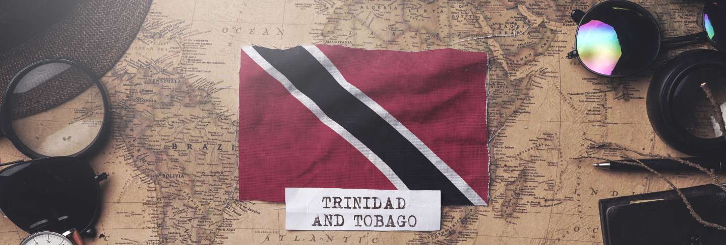 Trinidad and tobago flag between traveler's accessories on old vintage map. overhead shot