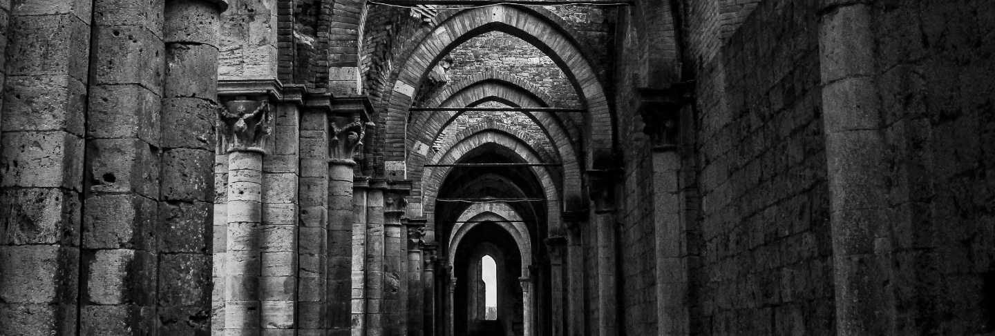 Vertical shot of a hallway with pillars and arched type doorways at abbazia di san galgano
