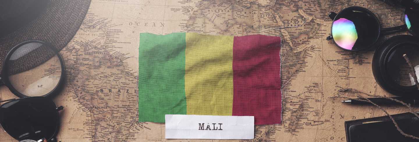 Mali flag between traveler's accessories on old vintage map. overhead shot
