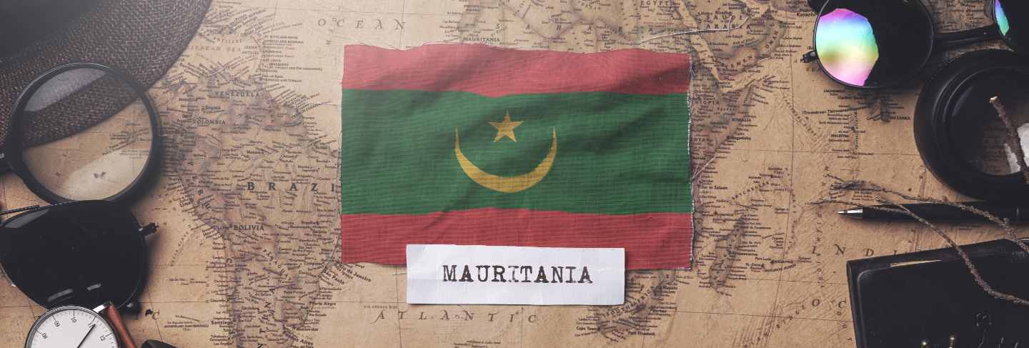Mauritania flag between traveler's accessories on old vintage map. overhead shot
