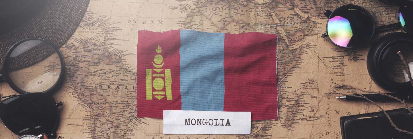 Mongolia flag between traveler's accessories on old vintage map. overhead shot
