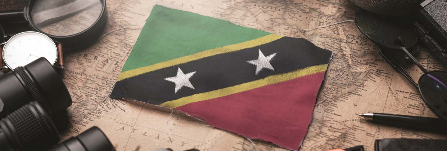 Saint kitts and nevis flag between traveler's accessories on old vintage map. tourist destination concept.
