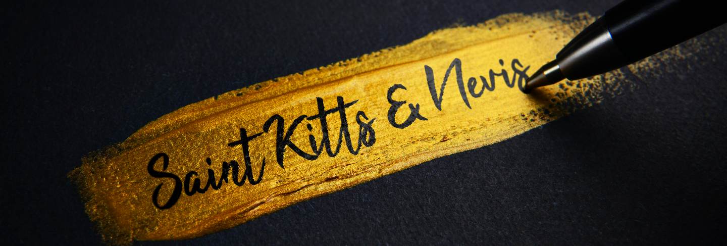 Saint kitts and nevis handwriting text on golden paint brush stroke
