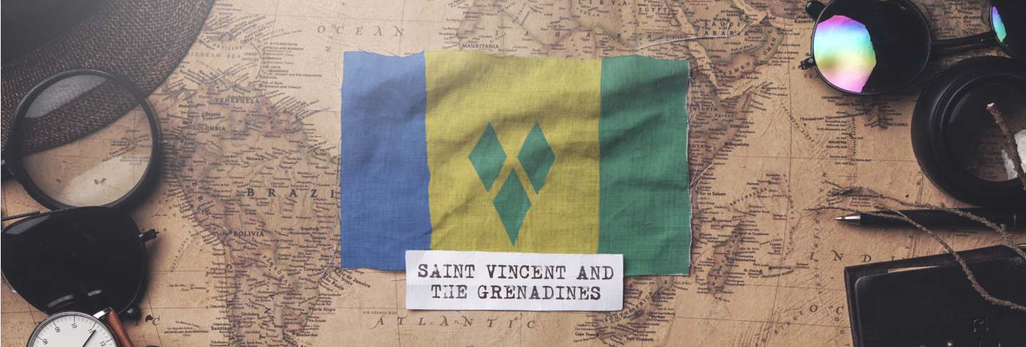 Saint vincent and the grenadines flag between traveler's accessories on old vintage map.
