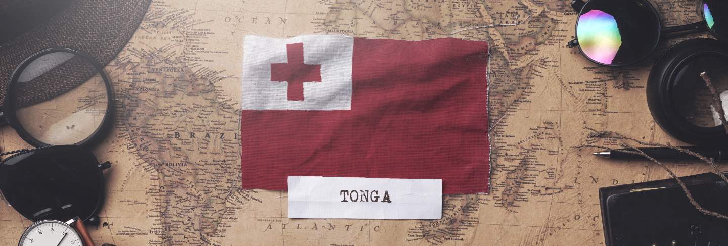 Tonga flag between traveler's accessories on old vintage map.