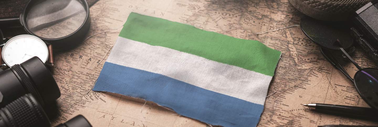 Sierra leone flag between traveler's accessories on old vintage map. tourist destination concept.
