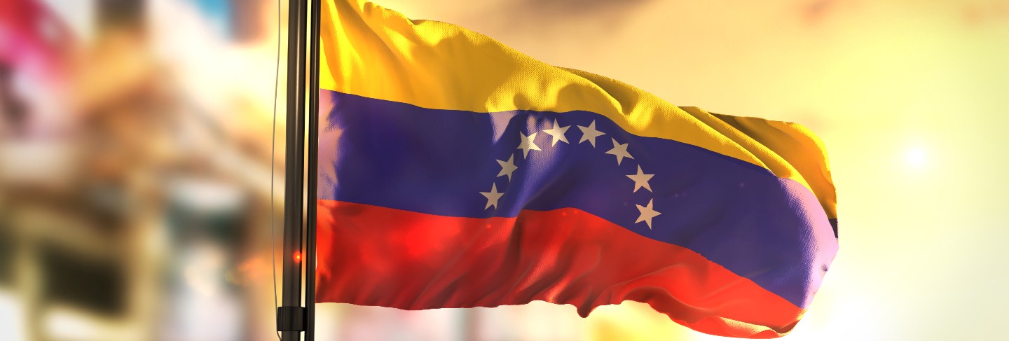 Venezuela flag against city blurred background at sunrise backlight