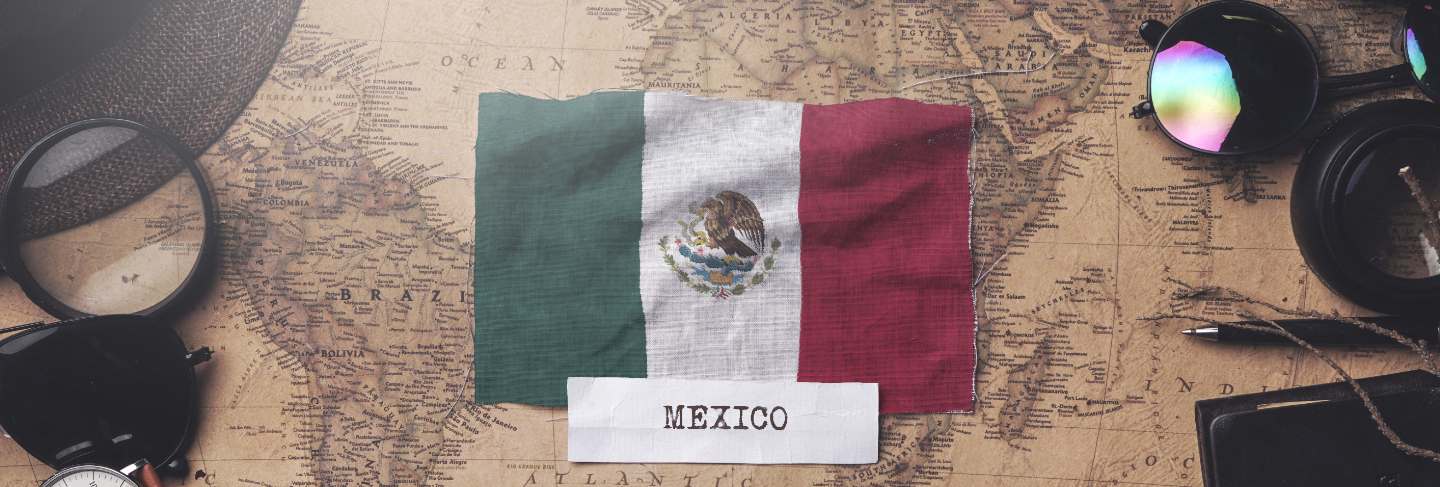 Mexico flag between traveler's accessories on old vintage map. overhead shot
