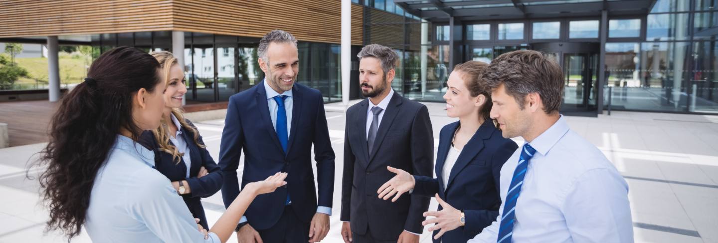 Group of businesspeople interacting outside office building 
