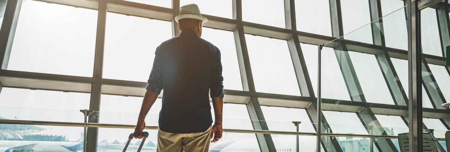 A male traveler wearing a gray hat preparing to travel
