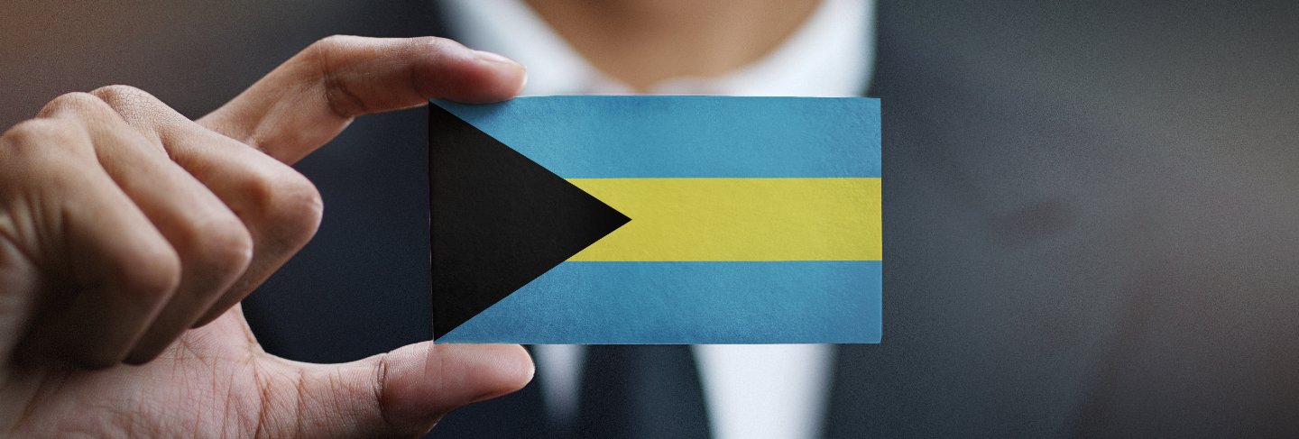 Businessman holding card of the bahamas flag
