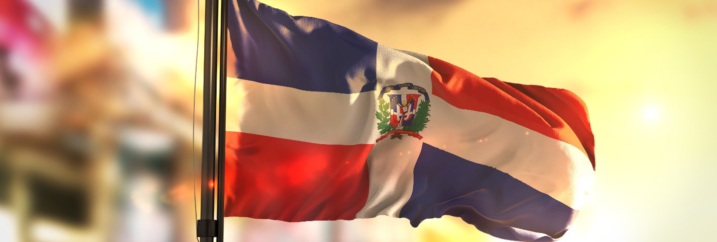 Dominican republic flag against city blurred background at sunrise backlight 
