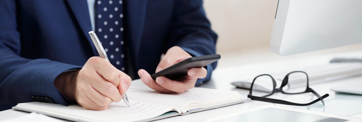 Cropped business man making notes from his smartphone calendar to the organizer
