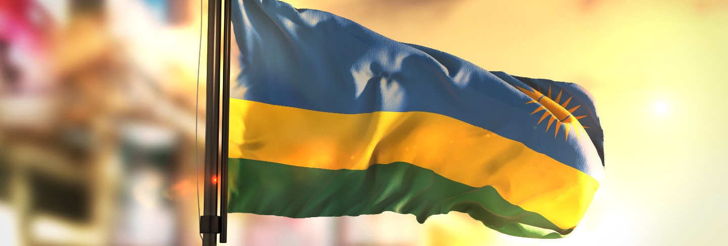 Rwanda flag against city blurred background at sunrise backlight
