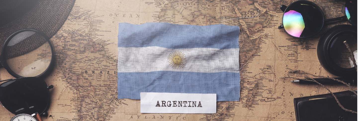 Argentina flag between traveler's accessories on old vintage map. overhead shot 